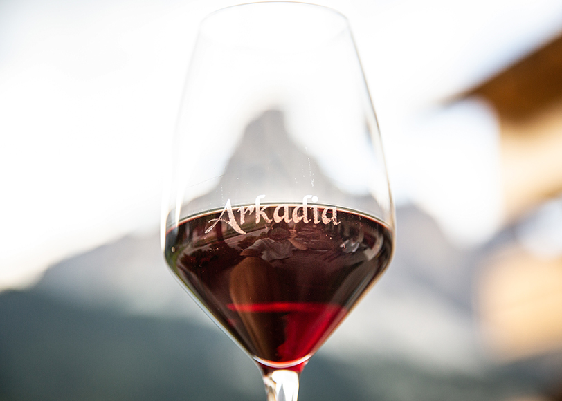 Calice di vino con logo Arkadia e Dolomiti sullo sfondo
